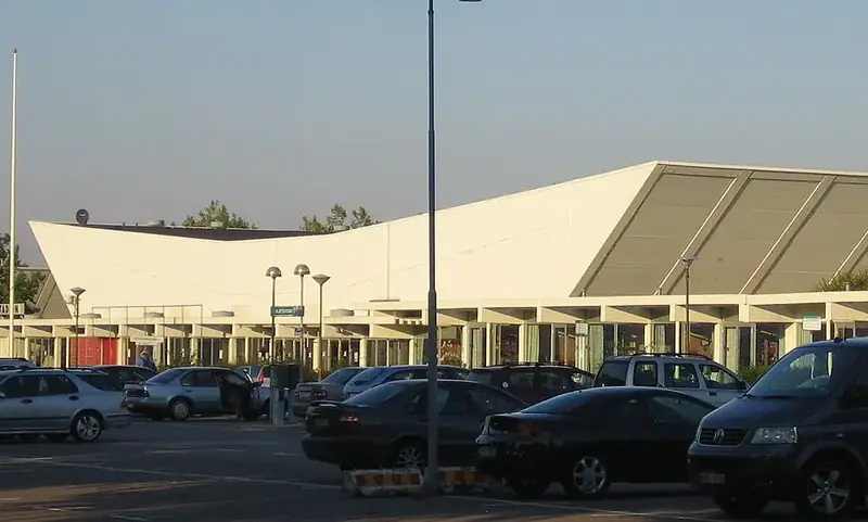 Isstadion i Malmö med vinklat tak sett från parkeringen framför entrén